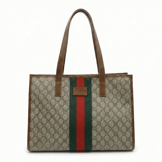 TKN Heritage tote bag featuring a signature brown monogram canvas, central green and red webbing stripe, and chocolate leather handles