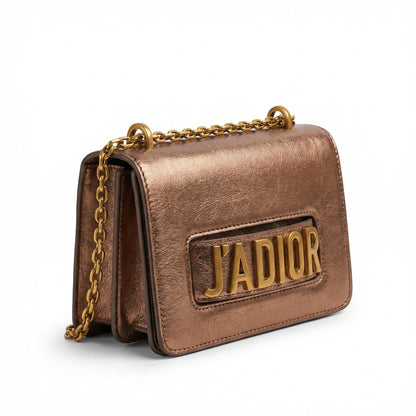 Quartz — A compact flap-style crossbody bag with a chain strap and metal accent.